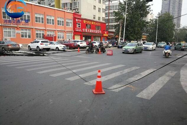郑州闹市区两根线杆连根拔起 几十根线缆垂落