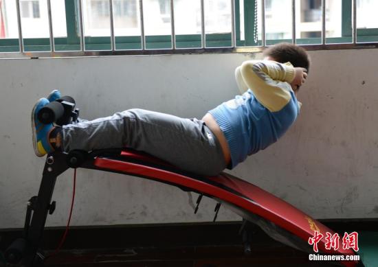 资料图：一名小胖墩儿们正在减肥训练课上做仰卧起坐。中新社发 李晨韵 摄