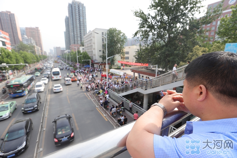 一位父亲将孩子送入考场后没有离去，在远处注视。