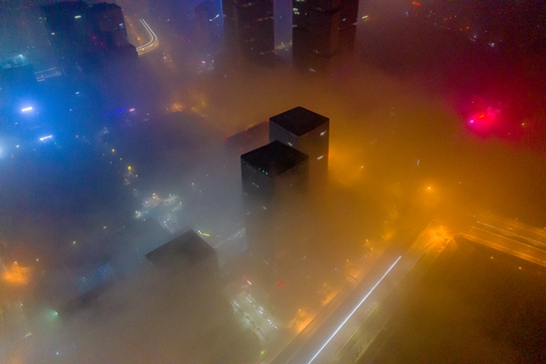 夜间整个城市都笼罩在升腾的云雾之中,仅有高层建筑露出顶部,若隐若现