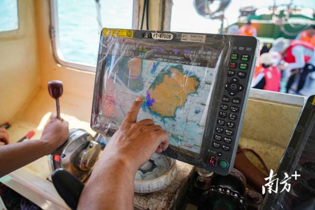 湛江东海岛龟头村渔民吴华雄对着渔船的地图导航，指出当地白海豚常出没的海域。